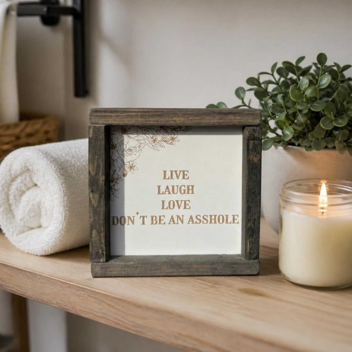 Live laugh love don't be an asshole framed sign on a bathroom shelf